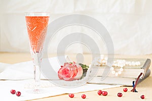 Glass of kir royal cocktail with vintage books and pearls