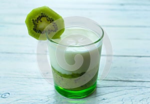 Glass of kiwi smoothie with yogurt on a white wooden background. Top view.