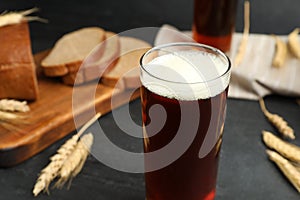Glass of kvass, bread and spikes on black table