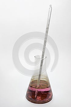 Glass laboratory flask, thermometer, pink solution
