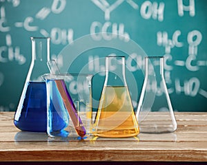 Glass laboratory flasks on wooden table