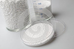 Glass laboratory jar with samples of white synthetic rubber on a white background