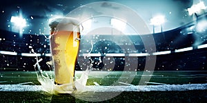 Glass with lager foamy beer on grass at soccer stadium. Game and drink, sports fan