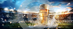 Glass with lager foamy beer on grass at soccer stadium. Game and drink, sports fan