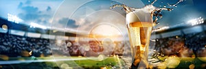 Glass with lager foamy beer on grass at soccer stadium. Game and drink, sports fan