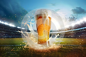 Glass with lager foamy beer on grass at soccer stadium. Game and drink, sports fan