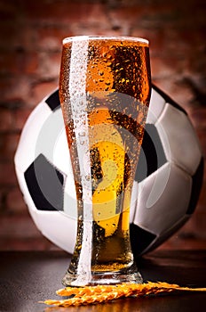 Glass of lager on table with soccer ball