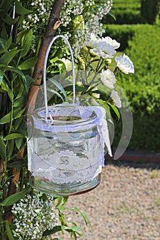 Glass lantern decorated with white lace hanging on wedding archw