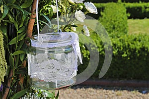 Glass lantern decorated with white lace hanging on wedding archw