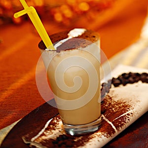 Glass of latte macchiato with chockolate powder and a straw
