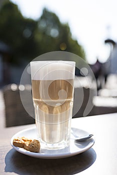 Glass of latte macchiato with spume, spoon and cookie