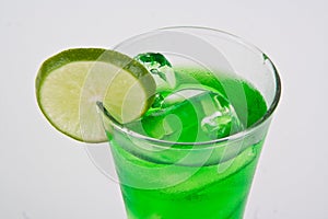 A glass of lemon green Italian soda with ice cubes isolated on white background. Homemade refreshment cold summer soft drink.