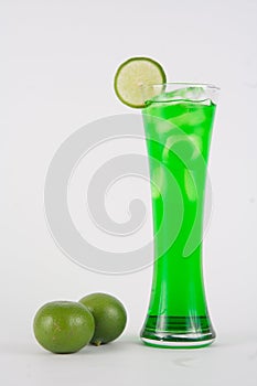 A glass of lemon green Italian soda with ice cubes isolated on white background. Homemade refreshment cold summer soft drink.