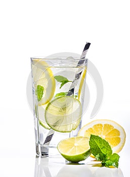 Glass of lemonade with lemon, lime and mint on white background