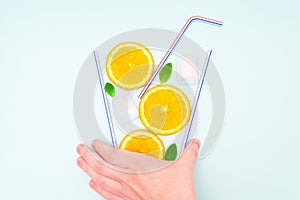 Glass of lemonade made of orange slices and drinking straws. Creative flat lay composition.