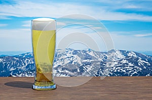 Glass of light beer against snow mountains