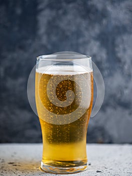 A glass of light beer on a dark background