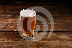 Glass of light beer on a dark pub. Glass beer on wood background with copy space