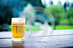 Glass of light beer with foam on a wooden table. Garden party. Natural background. Alcohol. Draft beer.