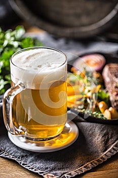 Glass of light beer in pub or restavurant on table with delicoius food