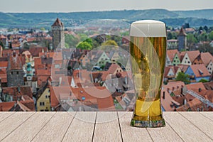 Glass of light beer on Rothenburg old town background. View from above with city wall and towers in Rothenburg ob der Tauber,