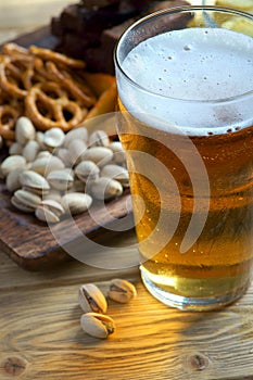 A glass of light beer and snacks on a dark background