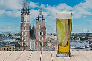 Glass of light beer on table in front of St. Mary\'s Basilica in Krakow, Poland