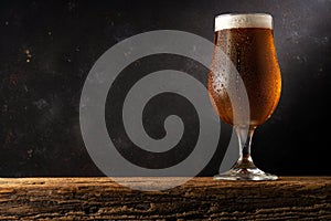 Glass of light beer on a wooden table. Dark background. Drink concept