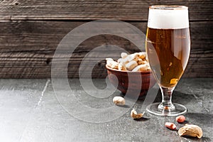 Glass of light cold frothy beer, nuts on an old wooden background