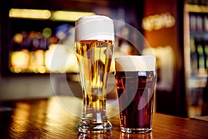 Glass of light and dark beer on a pub with bokeh background