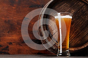 Glass of light lager beer and old wooden barrel