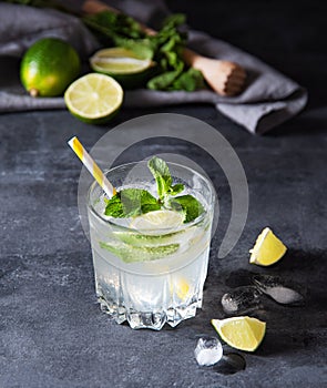 Glass of lime lemonade mojito  with lime slices, ice  and  mint on dark background. Close up