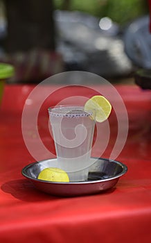 Glass of lime water or lemonade on a red  plastic top in a park