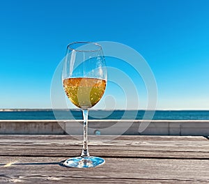 glass with limonade wooden table  on the beach in sea port blue sky  sun beam reflection and  scene