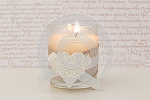 Glass with lit vanilla candle and white heart photo