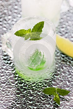 Glass made of ice with vodka, lemon and mint