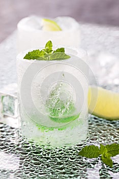 Glass made of ice with vodka, lemon and mint