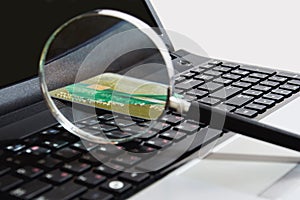 A glass magnifier lies on the keyboard along with a bank card in a cozy workplace