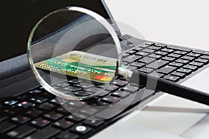 A glass magnifier lies on the keyboard along with a bank card in a cozy workplace