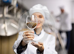 Glass with malted barley grain in hands of female brewmaster