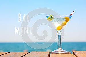 Glass of martini bianco at the wooden pier. Concept of summer vacation. Popular cocktail by the sea.. Bar menu wording