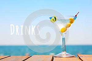 Glass of martini bianco at the wooden pier. Concept of summer vacation. Popular cocktail by the sea. Drinks wording