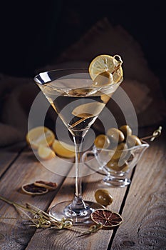 Glass of martini with green olives on a old wooden table