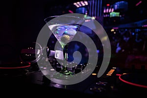 Glass with martini with olive inside on dj controller in night club. Dj Console with club drink at music party in nightclub with d