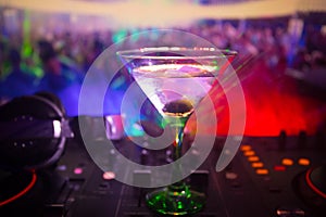 Glass with martini with olive inside on dj controller in night club. Dj Console with club drink at music party in nightclub with d