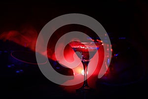 Glass with martini with olive inside on dj controller in night club. Dj Console with club drink at music party in nightclub with d