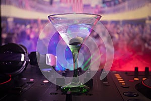 Glass with martini with olive inside on dj controller in night club. Dj Console with club drink at music party in nightclub with d