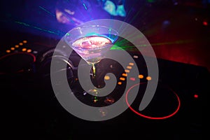 Glass with martini with olive inside on dj controller in night club. Dj Console with club drink at music party in nightclub with d