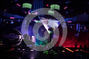 Glass with martini with olive inside on dj controller in night club. Dj Console with club drink at music party in nightclub with d