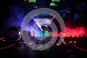 Glass with martini with olive inside on dj controller in night club. Dj Console with club drink at music party in nightclub with d